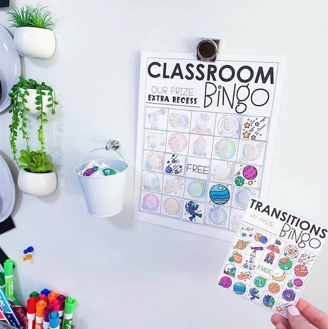 Classroom Management Bingo on whiteboard with a woman holding a desk size transitions bingo next to the large version